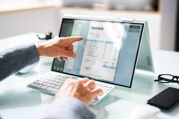 close up of businessman's hands working on invoice on laptop at office